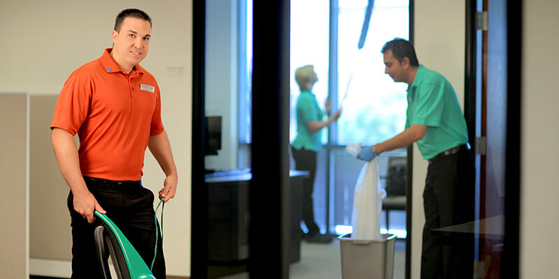 Floor Care careers - Man in orange shirt vacuuming. | MasterCorp Jobs - Hablamos español.